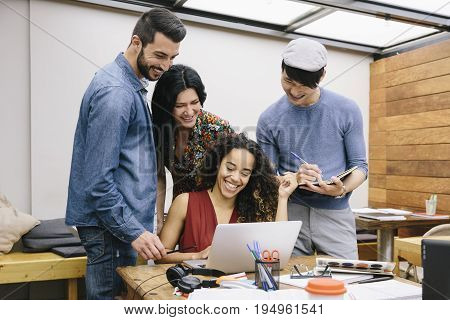 Startup of four multiethnic people discussing joyfully ideas in a modern coworking espace