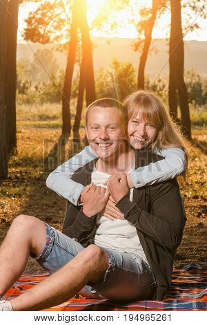 young loving couple in the Park sitting on a blanketthe girl embraces the guy