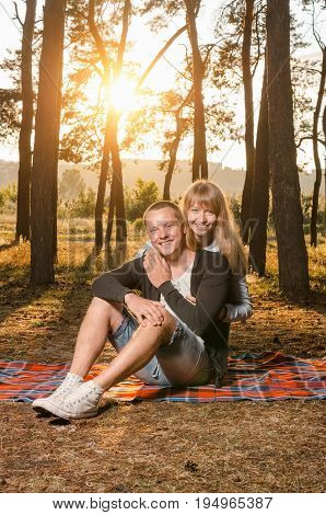 young loving couple in the Park sitting on a blanketthe girl embraces the guy