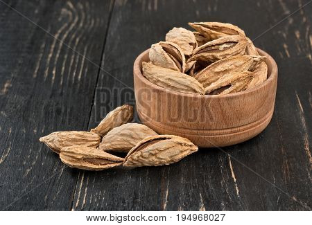 Wild uzbek inshell almonds in a bowl on wooden background
