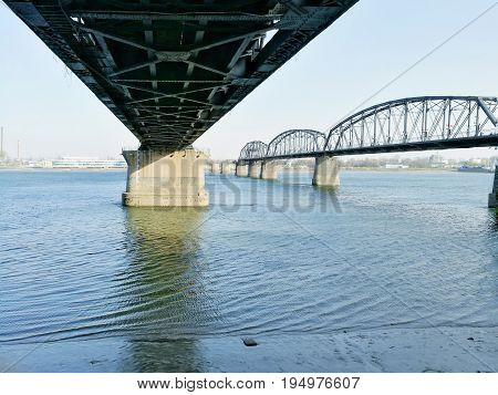 Beneath the bridge of China - North Korea 
Friendship with Broken Bridge on the right; across Yalu river. Taken in April, 2017, from public area in Dandong, Liaoning, China, opposite to Sinuiju, DPRK.
