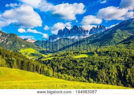 The green valley is surrounded by a dentate wall of dolomite rocks. Warm autumn in the Dolomites, the Val de Funes.  The concept of ecological tourism