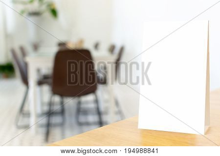 Mock up blank template menu frame on wood table in restaurant with blurred background Clipping path included