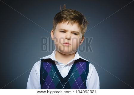 Closeup Portrait of handsome boy with astonished expression while standing against grey background.