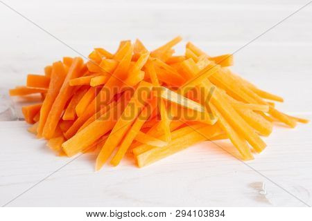 Lot Of Pieces Of Fresh Orange Carrot Cut Into Thin Noodles On White Wood