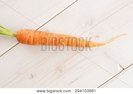 One Whole Fresh Orange Carrot With Greens Flatlay On White Wood