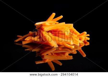 Lot Of Pieces Of Fresh Orange Carrot Cut Into Thin Noodles Isolated On Black Glass
