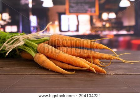 Lot Of Whole Fresh Orange Carrot Bunch With Greens Tied By Jute In A Restaurant