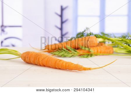 One Whole Fresh Orange Carrot In Focus With Greens With Blue Window In A White Kitchen