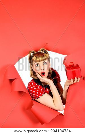 Surprised Retro Woman Hold Gift Box Through Hole In Paper. Woman With Present Looking Through Hole. 
