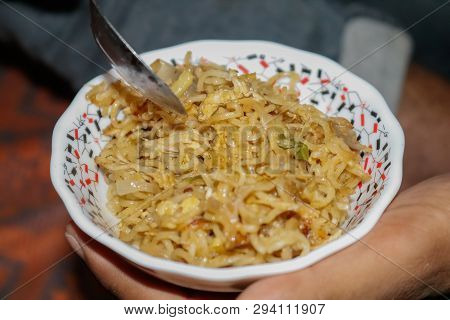 Someone Eating Noddles In A White Plate With Spoon.