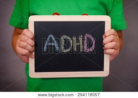 Young Boy Holds Adhd Text Written On Blackboard. Adhd Is Attention Deficit Hyperactivity Disorder. C