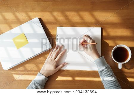 Asian Women Are Taking Notes On A Wooden Table With Coffee Mugs And Laptops At Home.