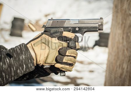 Close-up Detail View Of Hands In Gloves Holding Gun