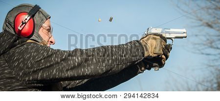 Shooter Holding Gun In Hand And Shooting. Close-up Detail View