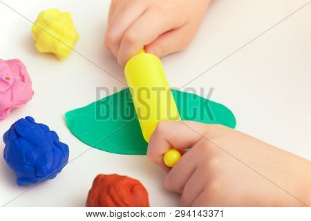 Child Playing Colorful Playdough On A Table. Close Up.