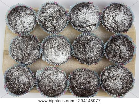 Chocolate-banana Muffins With Sugar Powder On A Wooden Board On A White Background. View From Above.