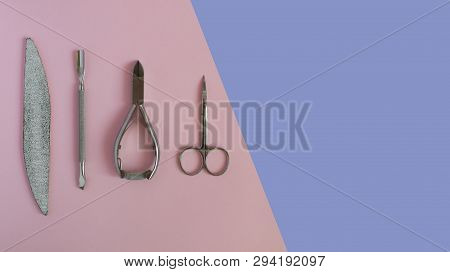 Manicure Tools On A Pink And Violet Background. Cuticle Scissors, Nail Scapula, Nail File, Nail Clip
