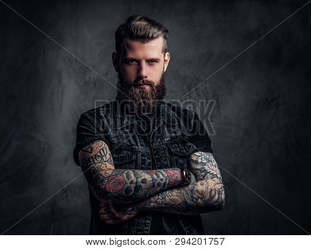 Portrait Of A Tattooed Man With Beard And Hairstyle Posing With His Arms Crossed. Studio Photo Again