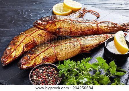 Hot Smoked Whole Herrings With Lemon Slices, Parsley And Peppercorns On A Black Slate Tray  On A Woo