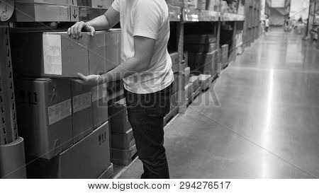 Warehouse Large Storage Or Logistic Or Cargo For Distribution. And Man's Hand Is Picking Up A Box.