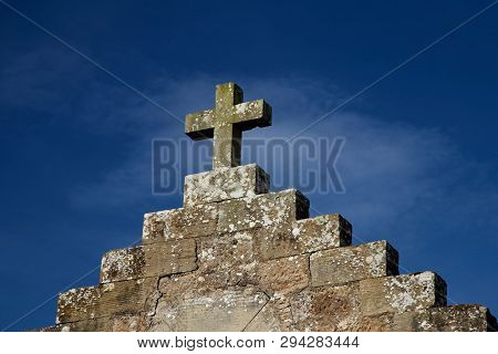 Stone Cross On Old Building Against A Blue Sky