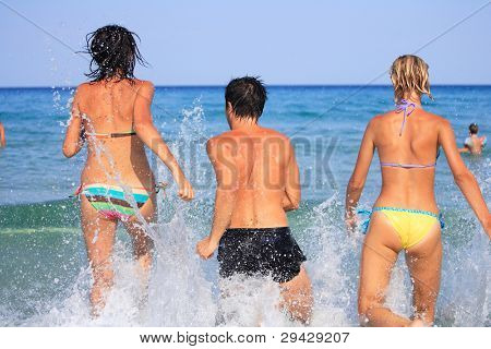 Gruppo di tre amici - uomo e donna - sulla spiaggia avendo un sacco di divertimento in vacanza in Grecia