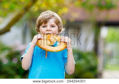 Adorable Little Kid Boy Eating Huge Big Bavarian German Pretzel. Happy Blond Child Enjoying Tasteful