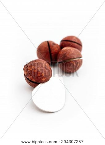 Three Macadamia Nuts With Metal Shell Opener, Isolated On White Background.