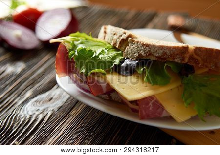 Sandwich With Bacon, Cheese And Herbs On A Plate, On A Wooden Background