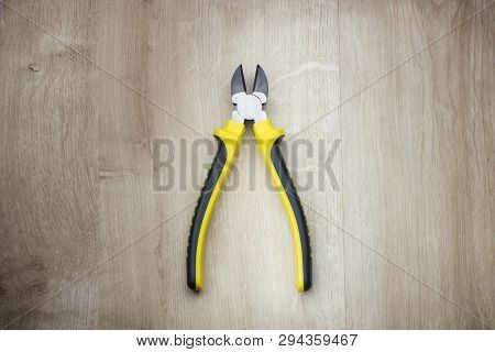 Top View On Yellow Side Cutters On Wooden Background.