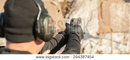 Shooter Holding Gun In Hand And Shooting. Close-up Detail View