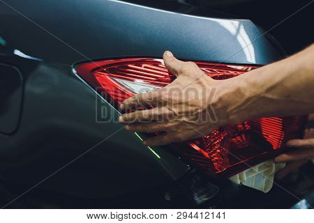 Mechanic Matching Automobile Headlight Lamp To Damaged Car At Repair Service Station.