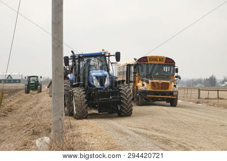 April 06 2019, Elmira Canada: Editorial Photo Of A School Bus Driving By A Tractor. Elmira Is Known 
