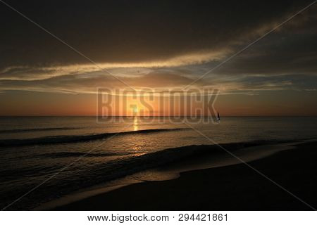 Captiva Island, Florida 08-05-2015 Small Sailboat In Partial Silhouette Against The Setting Sun In T