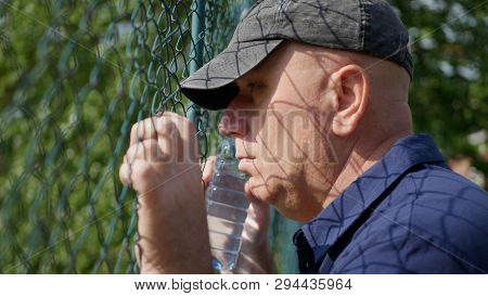 Disillusioned Man Looking Sad Thru A Metallic Fence