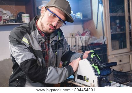 Portrait Of Dilly Young Carpenter Working With An Electrical Plane In A Home Wood Workshop. The Conc