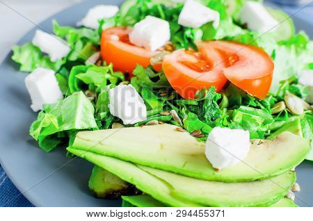 Fresh  Green Salad With Cucumber, Lettuce, Avocado, Tomatoes And Soft Cheese And Glass Water On The 