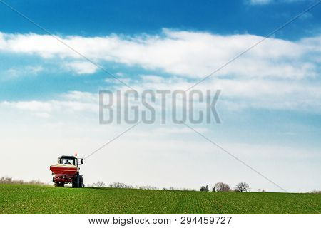 Unrecognizable Farmer In Agricultural Tractor Is Fertilizing Wheat Crop Field With Npk Fertilizer Nu