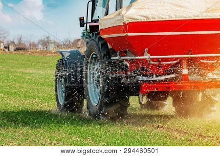 Unrecognizable Farmer In Agricultural Tractor Is Fertilizing Wheat Crop Field With Npk Fertilizer Nu