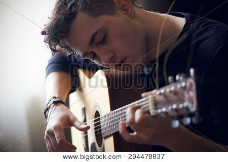 Curly Young Musician In Black Clothes Performs Solo On Acoustic Six-string Guitar