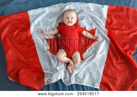 White Caucasian Smiling Baby Boy Girl With Blue Eyes Lying On Large Canadian Flag With Red Maple Lea