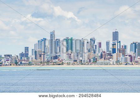 Seafront City. Touristic City With A Beach, Banks Of Corals On The Sea At Low Tide And Tall Building