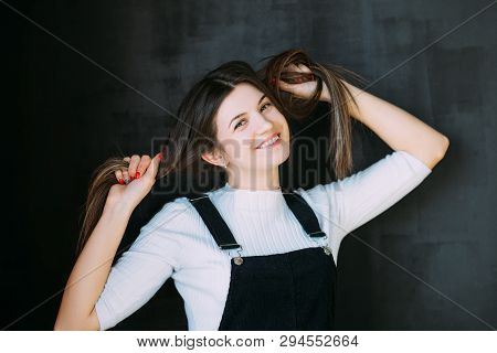 Portrait Of Playful Brunette Girl On Dark Background. Beautiful Emotional Lady Pulling Hair Aside. D