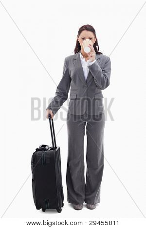 Businesswoman with a suitcase drinking a coffee against white background