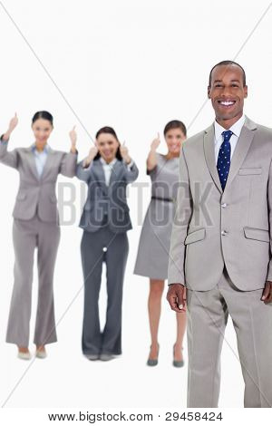 Happy businessman with three approving co-workers in background with thumbs up