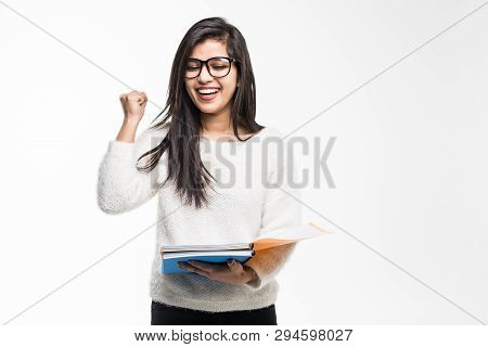 Portrait Of Attractive Indian Student Woman Standing Holding Reading A Book With Win Gesture Over Wh