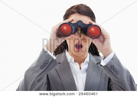 Close-up of a surprised businesswoman looking through binoculars against white background