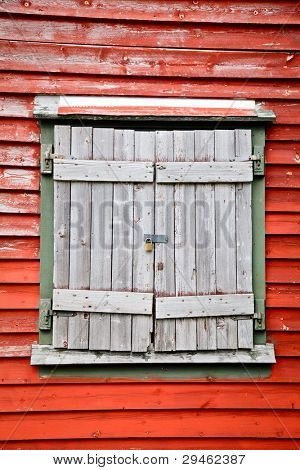 Staré omšelé dřevěné uzávěrkou okna na červenou zeď uzamčen