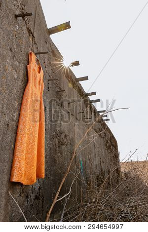 Orange Dress With Gold Thread On The Falling Down Wall